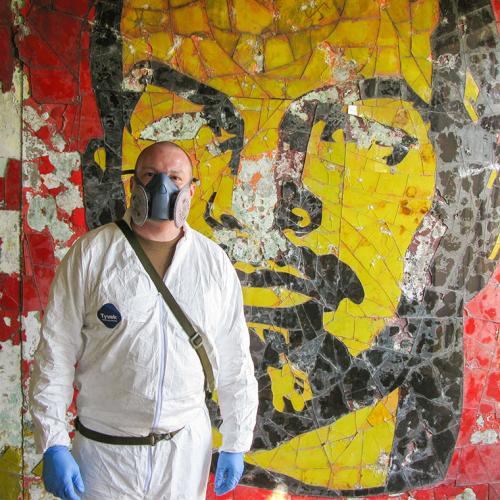 Major Gary Johnston wears a gas mask and environmental boiler suit as he stands by a mural in an abandoned building.