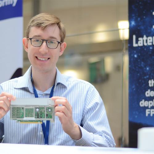 Andrew Canis smiles as he holds up a computer circuit board.