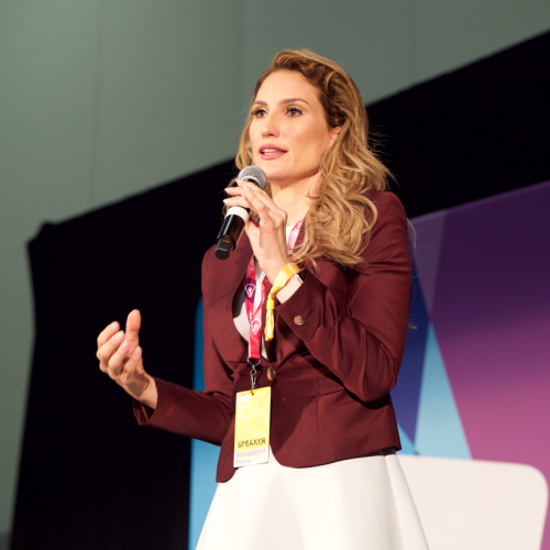 Lorraine D'Alessio stands on a stage, giving a presentation.