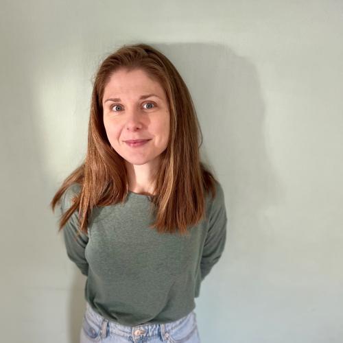 A portrait of Lucy standing in front of a wall