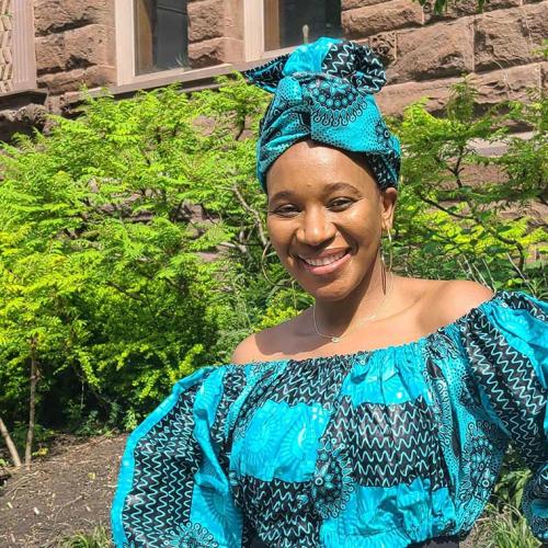 Matida Daffeh smiling and standing in a garden.