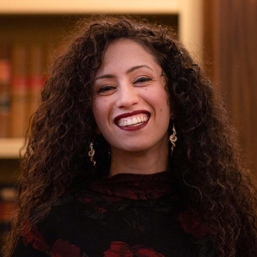 Mikaela Gabriel laughs happily, standing in a library.