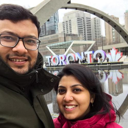MD Nafizuzzaman and his wife smile as they take a selfie at City Hall, in front of the giant letters spelling TORONTO.