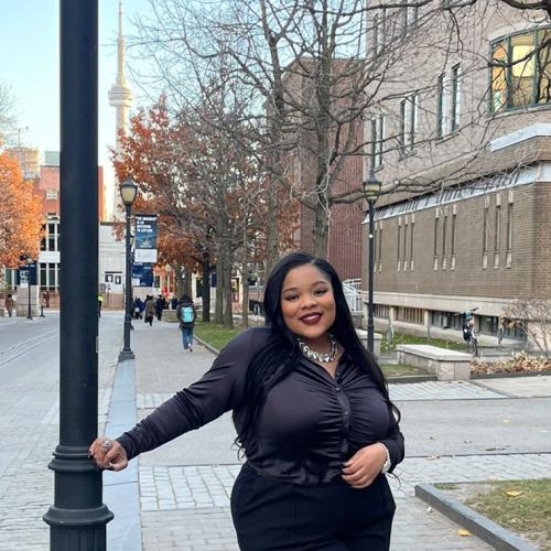 Lashae Watson smiles happily as she leans on an iron lamp post at a street corner on St. George campus.
