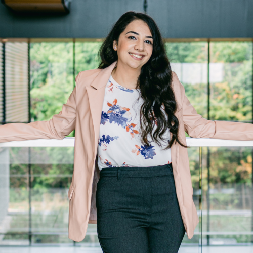 Anureet smiling and standing in front of a large bank of windows