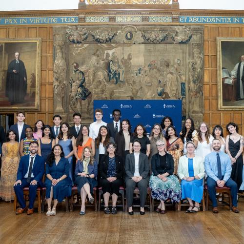 A group of people sitting and standing in a formal university hall