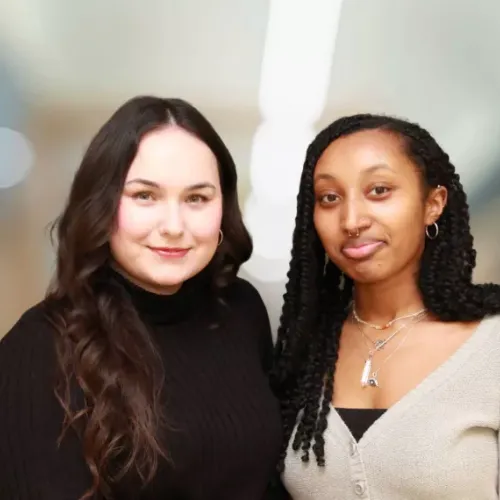 Two young women standing in front of a blurry background
