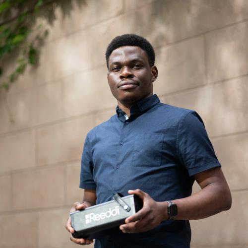 Olugbenga Olubanjo smiles as he holds a loaf-sized black box with the word Reeddi on the side.