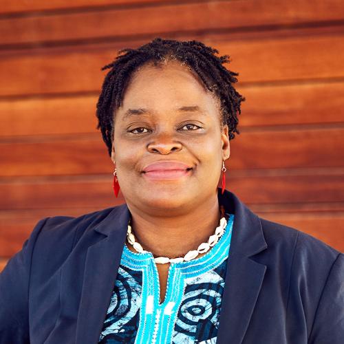 Roberta Timothy smiles, standing in front of some wood panelling.