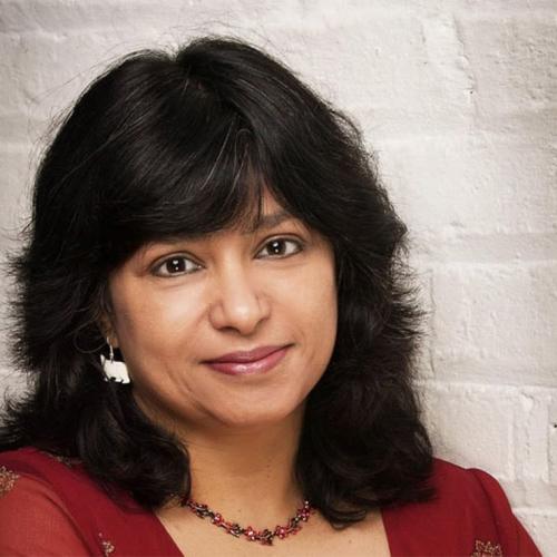Anna Banerji looks thoughtful, standing by a painted brick wall.
