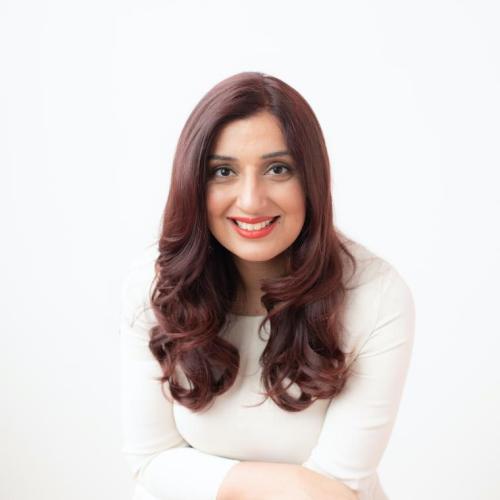 Portrait of Samra Zafar leaning forward and smiling.