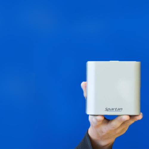 A hand holds up a smooth metal cube labelled: Spartan.
