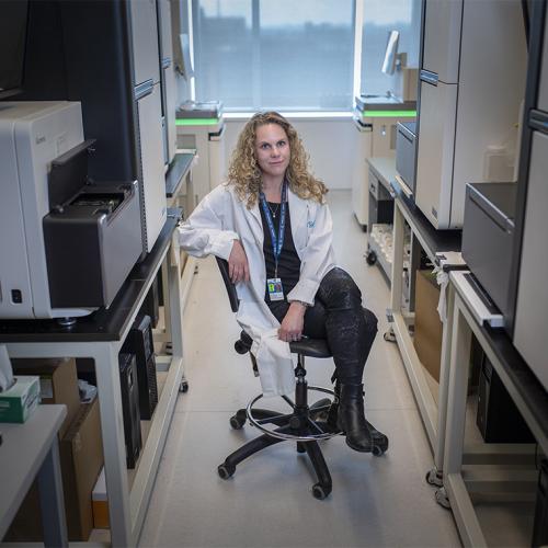 Lisa Strug sits on a chair between fridges and other lab equipment.