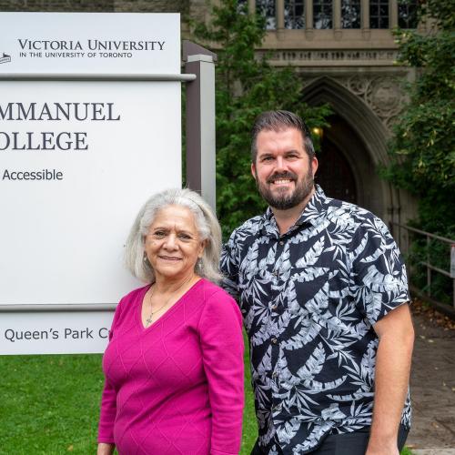 Two people standing in front of the Emmanuel College sign