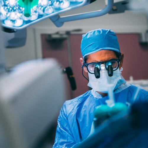 Neurosurgeon Taufik Valiante in an operating room, looking closely at a small machine 