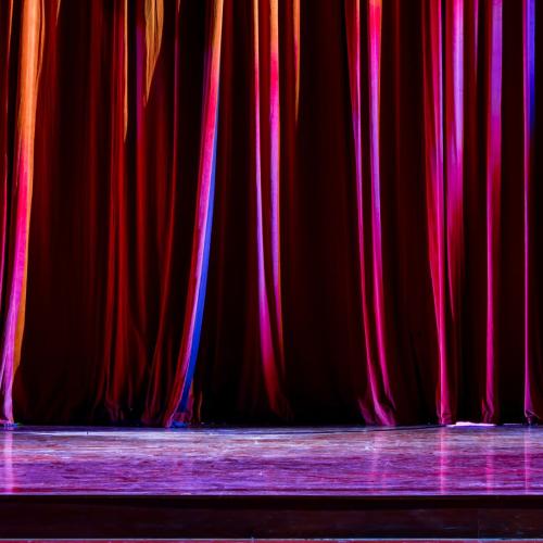 A red curtain pulled across a theatre stage
