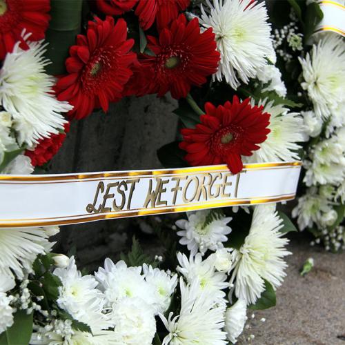 Bunches of flowers with a ribbon that reads, Lest we forget.