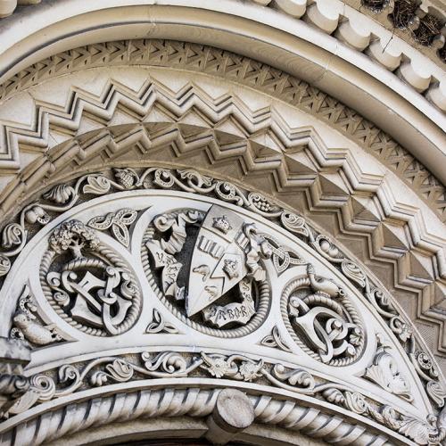 An elaborately carved stone archway with the U of T crest at the apex.