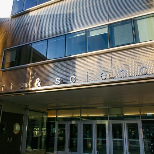 The glass doors to Sidney Smith Hall are sheltered under a sign reading: Arts & Science.