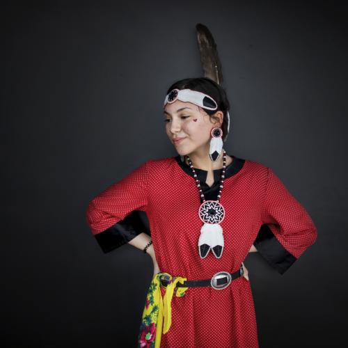 Dancer Miyopin Cheechoo wears traditional clothing, including a large feather.
