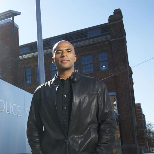 Akwasi Owusu-Bempah stands in front of a sign that reads Toronto Police Station.