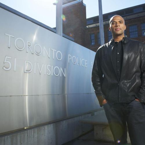 Akwasi Owusu-Bempah stands beside a Toronto police sign