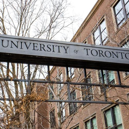 A metal sign reading, University of Toronto, bridges two stone pillars.