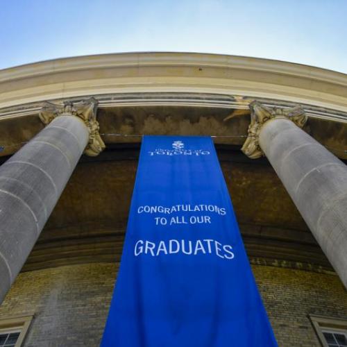 A banner reading Congratulations to our graduates hangs between the pillars outside Convocation Hall.
