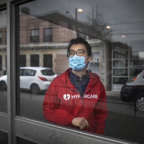 Albert Tai wears a mask and a Hypercare hoodie as he gazes thoughtfully out of a hospital window.