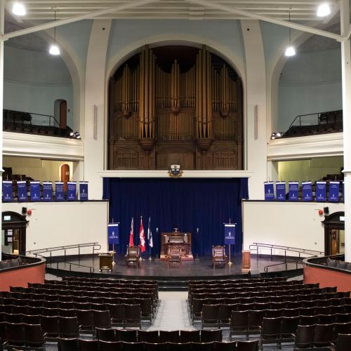 A dramatic view of the Convocation Hall interior: three levels with balconies, huge pipe organ, curving rows of wood seats.