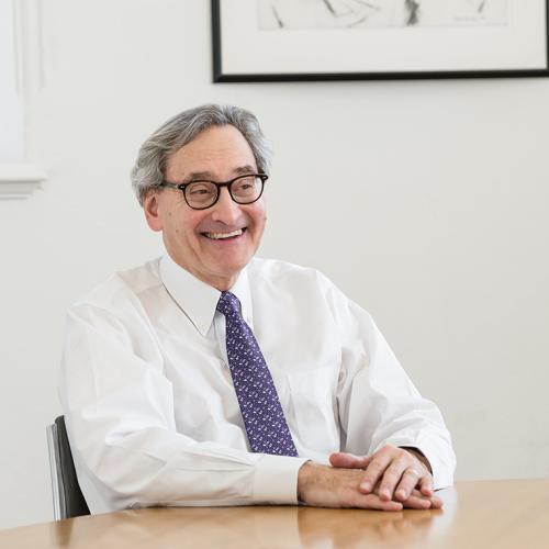 MIchael Sabia laughs while sitting with his hands folded on a desk.