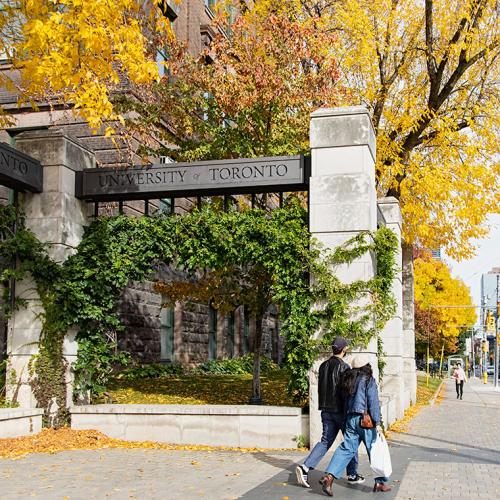 Metal beams (engraved with the words University of Toronto) rest across stone pillars to form U of T’s Alumni Gates. 