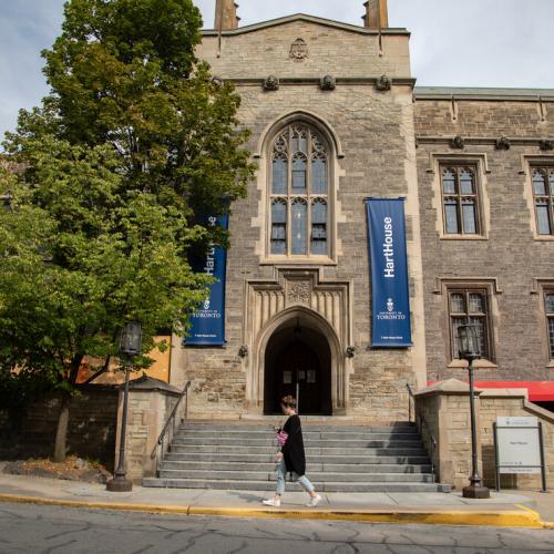The entrance to Hart House, an old stone building with ivy on the walls, and steps going up to an arched doorway.