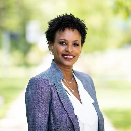 Rhonda McEwen smiles, standing outdoors in a park.