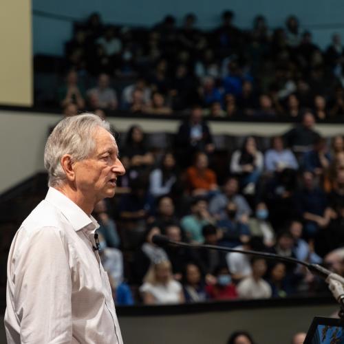 Geoffrey Hinton speaking on stage at Convocation Hall