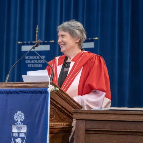 Helen Clark stands at a podium in a gown giving a speech at convocation.