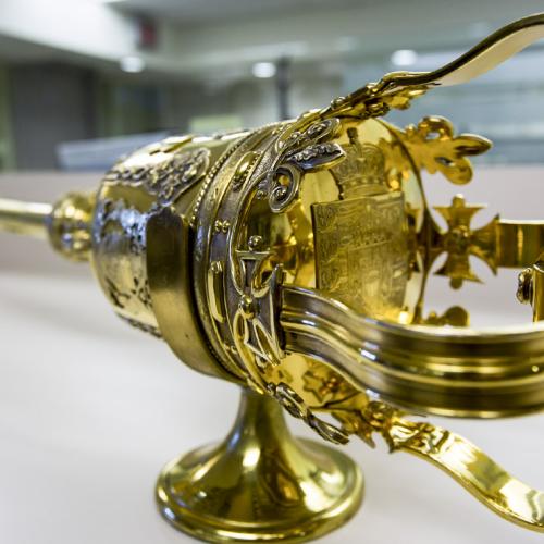 U of T's ceremonial mace likes on a table - an elaborate metal rod with a large old-fashioned crown shape on top.