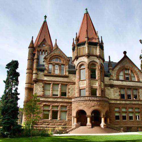 Victoria College's main building on a sunny day. The building has several elaborate turrets and spires.