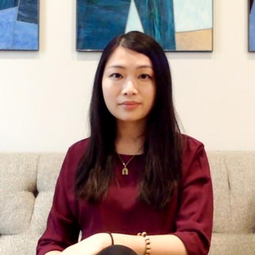 Vincci Liu looks serious as she sits on a sofa beneath colourful artworks.