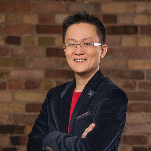 Allen Lau smiles as he stands with arms folded.