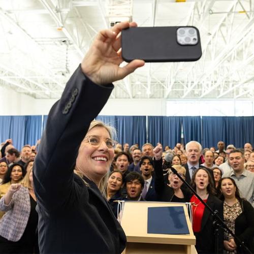 Melanie Woodin taking a selfie in front of an audience