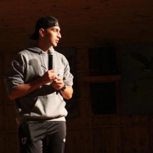 Yahya Ali stands on a stage holding a microphone.