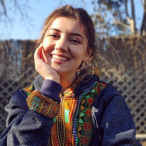 Portrait of Zarina Mamadbekova smiling and wearing a jacket with elaborately patterned trim.