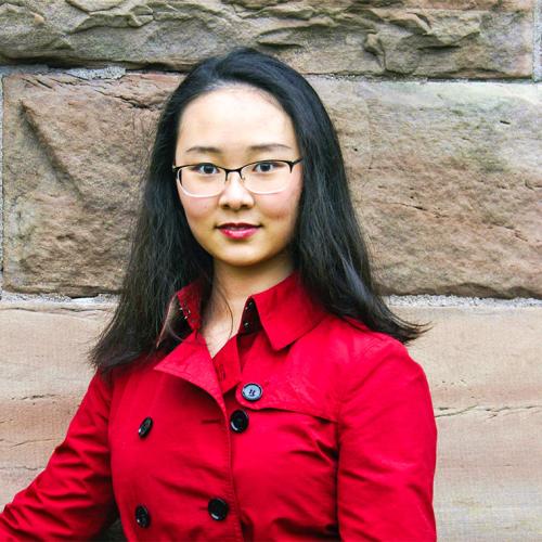 Zihan Gao smiles, standing in front of a stone wall outdoors.