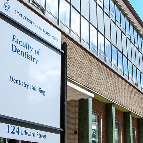 A sign saying University of Toronto Faculty of Dentistry outside a large building on Edward Street.