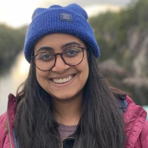 Aarohi Pathak smiling by a lake in the mountains.