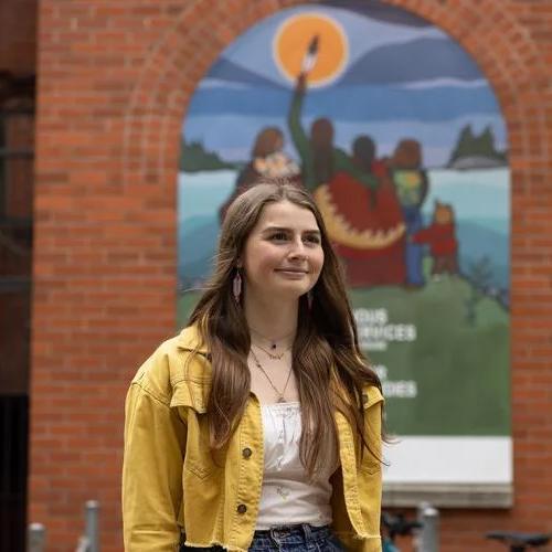 Alicia Corbierre standing outside with a mural behind her