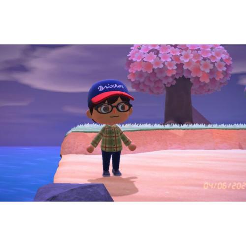 A cartoon boy in a baseball hat and glasses stands on a cartoon seashore by a fantastical tree.