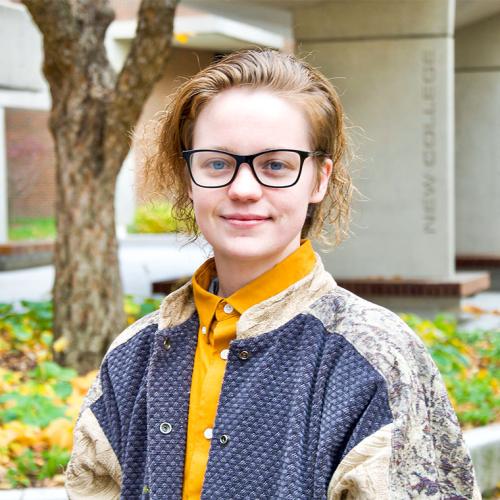 Chandler Fitzpatrick smiles while standing in front of a planter at New College Plaza.