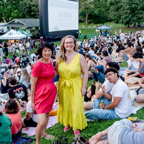 Emily Reid and Olivia Chow pose for a photo in front of an outdoor film audience
